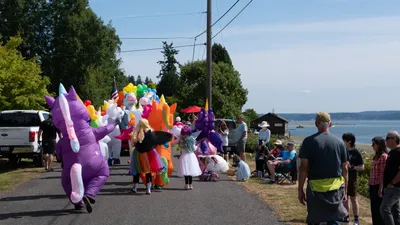 A colorful procession of inflatable costumes marches along the waterfront during the Fourth of July parade in Home, Washington.